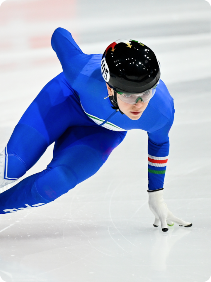 Speedskater Arianna Fontana rounding a turn on the ice wearing a team Italy speed skating suit