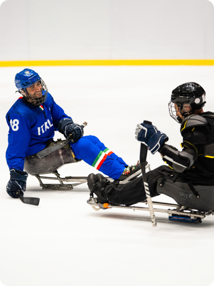 Paralympic Andrea Macrì on the ice surrounded by a cloud of ice spray wearing a team Italy jersey
