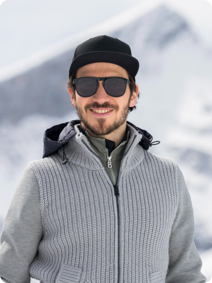 German Alpine skier Felix Neureuther smiles towards camera wearing casual winter clothes, a hat, and sunglasses