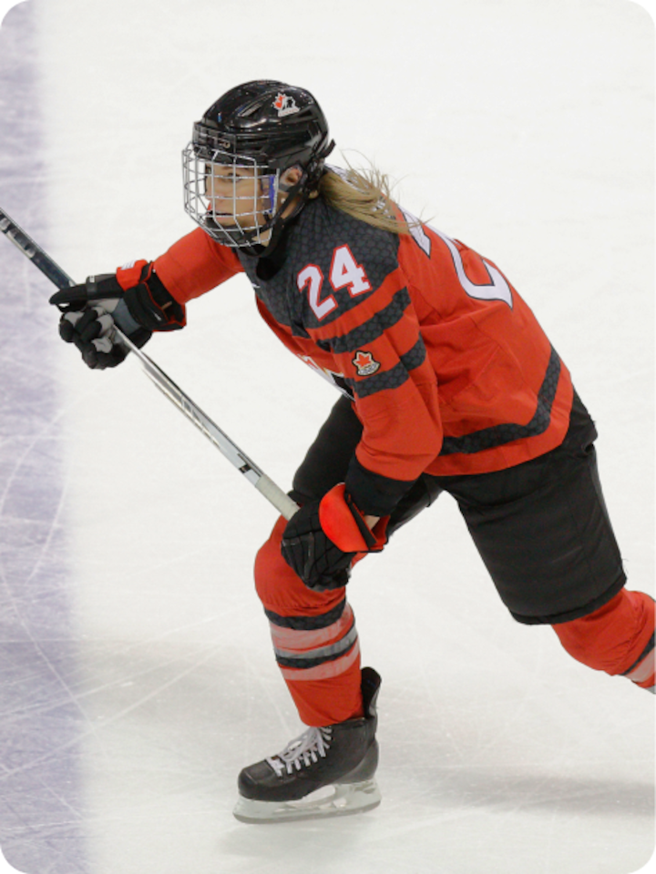 Hockey player Natalie Spooner skating with a raised hockey stick wearing team Canada uniform