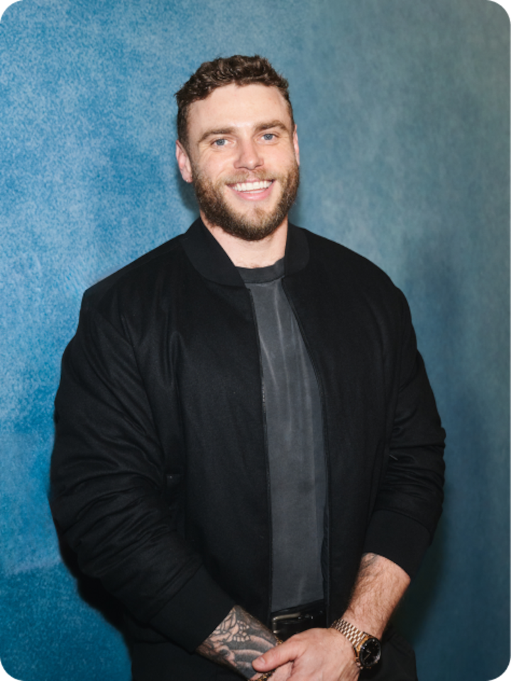 Gus Kenworthy smiles to the camera wearing street clothes