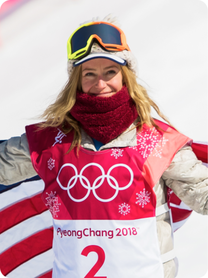 Jamie Anderson smiles in celebration post-race. She has an american flag draped over her shoulders