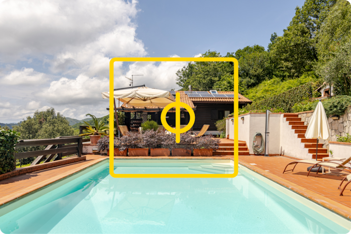 Une piscine extérieure paisible entourée de carreaux en terre cuite, de chaises longues et d'une maison à flanc de colline avec un toit en tuiles rouges et des panneaux solaires, le tout dans un cadre luxuriant et sous un ciel bleu.