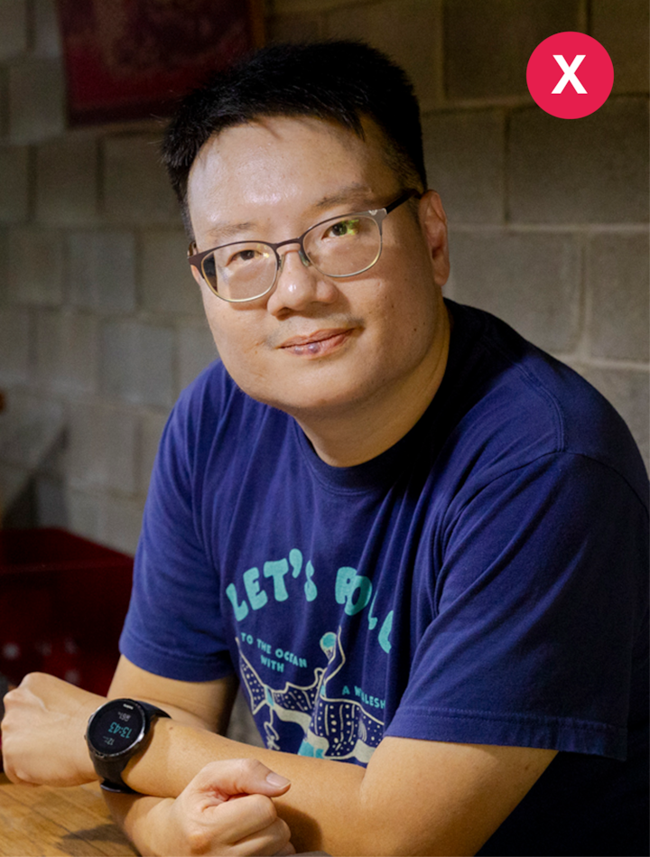 Plan rapproché d'une personne portant une montre connectée et un t-shirt bleu marine avec du texte et des illustrations sur le thème de l'océan, assise en intérieur contre un mur de briques grises.