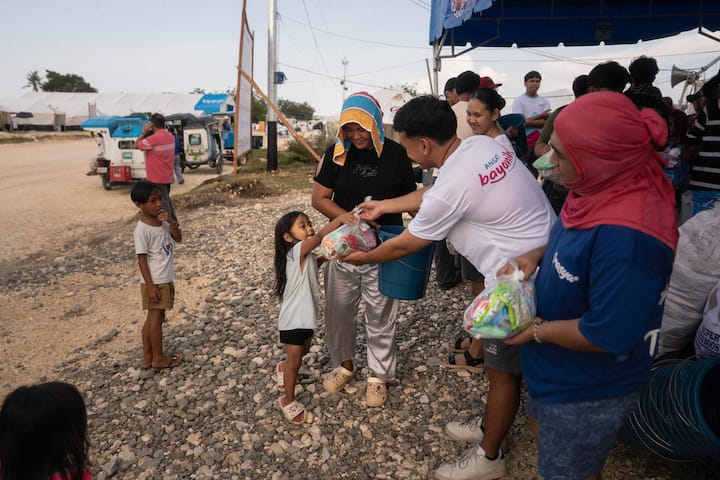 En frivillig fra Angat Buhay gir forsyninger til et lite barn etter jordskjelvet på 6,9 på Richters skala i Cebu på Filippinene.