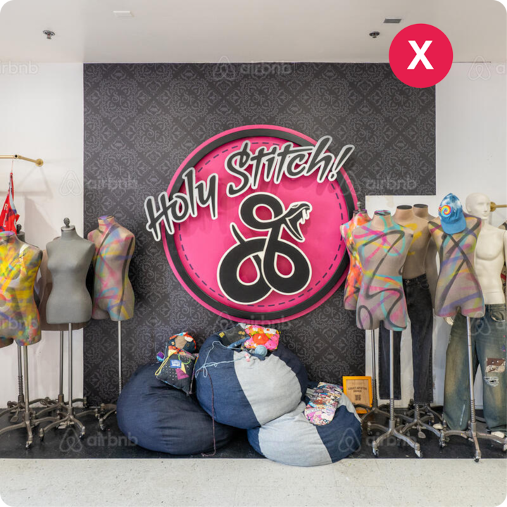 Des mannequins artistiques peints de manière créative se tiennent à côté d'un panneau rose indiquant « Holy Stitch ! » avec des sacs en jean et des outils de couture disposés en dessous.