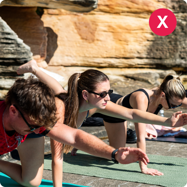 Un cours de yoga en plein air avec des personnes prenant des poses sur des tapis avec des falaises en arrière-plan.