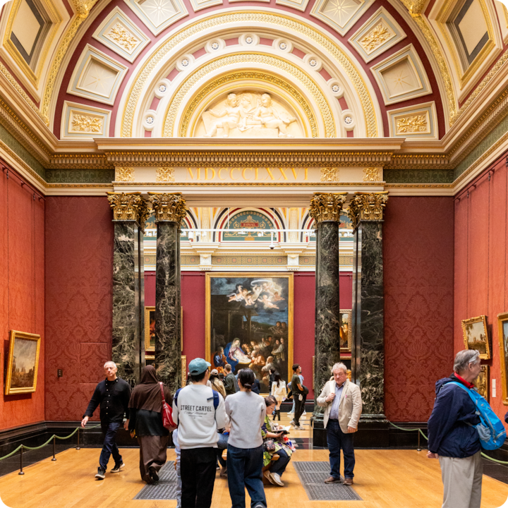 Une galerie élégante avec des piliers en marbre et des œuvres d'art historiques, mettant en valeur une peinture centrale entourée de visiteurs du musée qui interagissent avec l'espace.