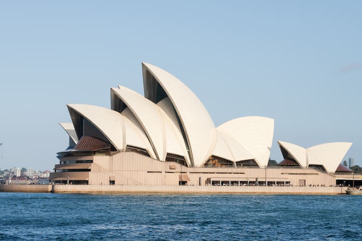 Sydney Opera House overlooking the harbor on a sunny day, a well-known landmark in New South Wales.