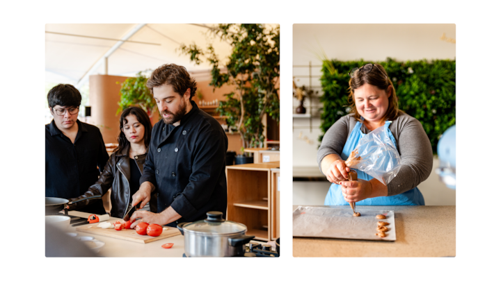 Un chef montre comment couper des tomates à un groupe de participants dans une cuisine lumineuse et moderne avec de la verdure en arrière-plan. Sur la droite, une personne dépose de la pâte sur une plaque de cuisson à l'aide d'une poche à douille lors d'un atelier culinaire.