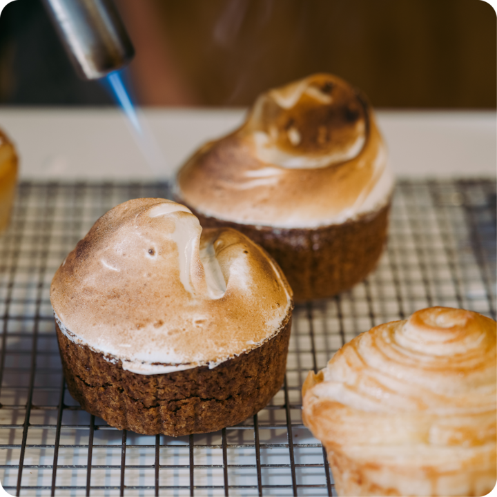 Gros plan sur des pâtisseries caramélisées avec un chalumeau de cuisine lors d'une expérience culinaire.