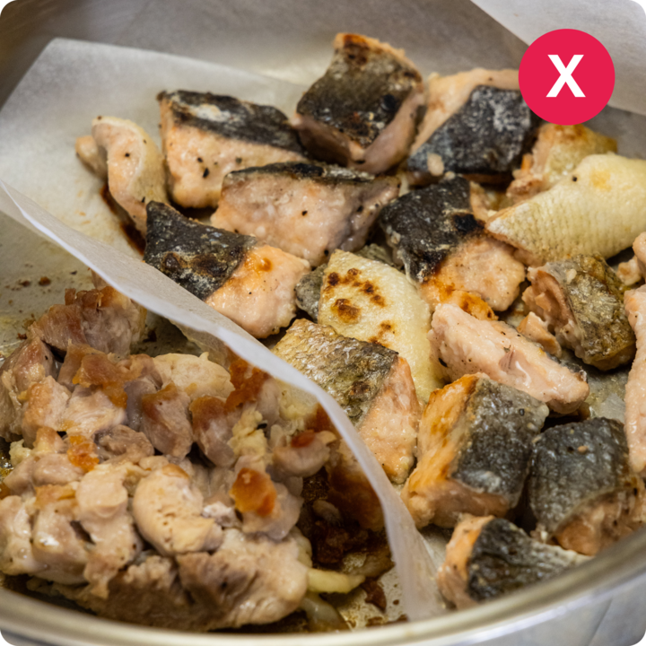 Un plateau de morceaux de saumon secs et trop cuits barré d'une croix rouge, illustrant une erreur de cuisson courante lors de la préparation du poisson.