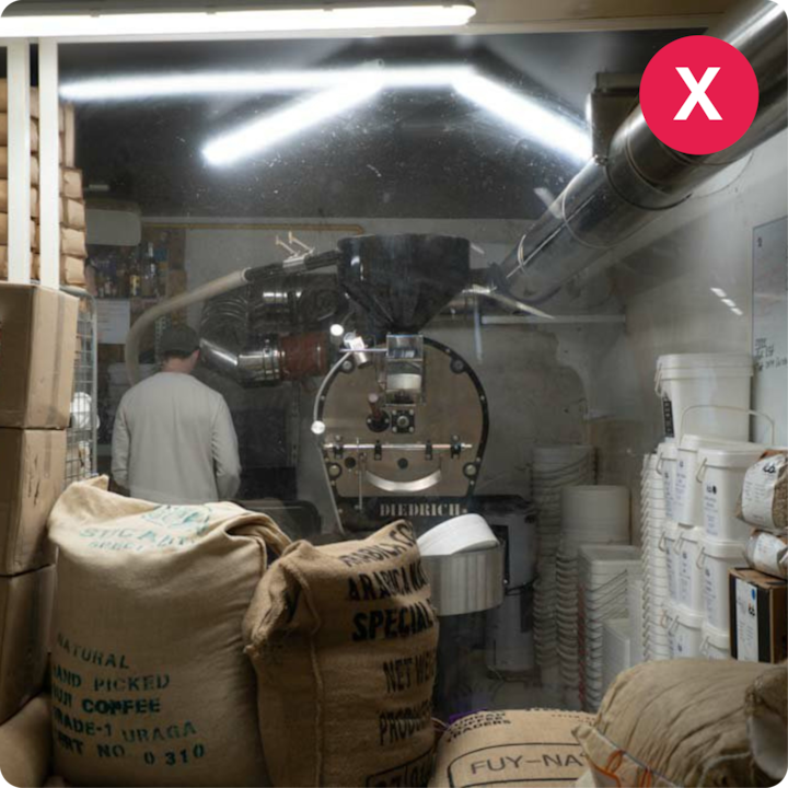 Une station de torréfaction de café avec des sacs de grains de café cru étiquetés avec des détails sur leur origine, et un hôte travaillant en arrière-plan près de la machine.
