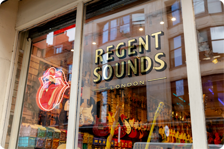 L'extérieur de Regent Sounds à Londres, avec des reflets des bâtiments voisins et des guitares visibles à travers la vitrine.