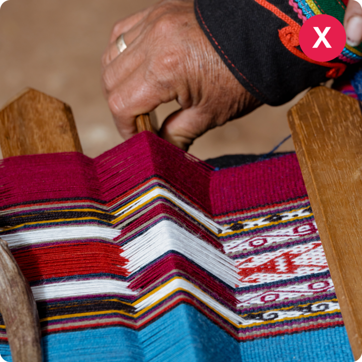 Une personne travaillant sur un métier à tisser en bois, créant un textile vif avec des motifs géométriques rouges, bleus, jaunes et blancs.