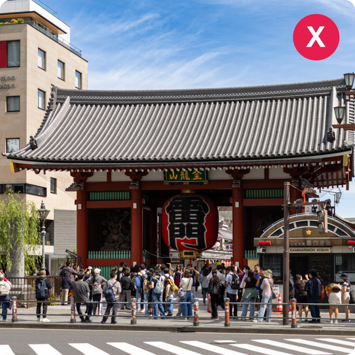 Des touristes se tiennent devant la porte Kaminarimon du temple Sensoji, un célèbre monument culturel de Tokyo, au Japon, sous un ciel bleu vif.