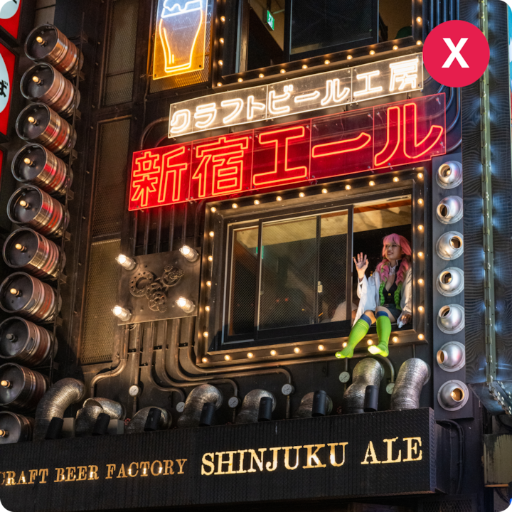 Vue nocturne d'une brasserie à Shinjuku avec des néons lumineux et des fûts de bière empilés verticalement le long de la façade du bâtiment.