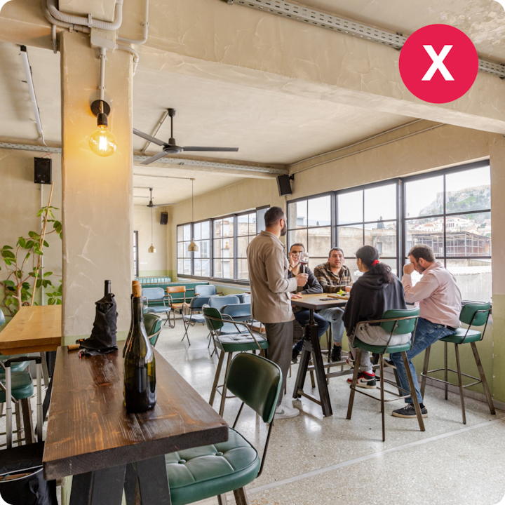 Un groupe de personnes assises écoute les explications d'un guide lors d'une dégustation dans un café moderne et bien éclairé, avec de grandes fenêtres.