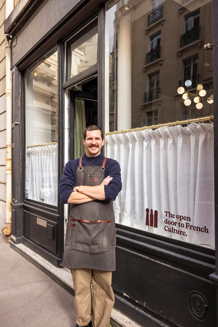 Erwan standing in front of wine shop with arms folded