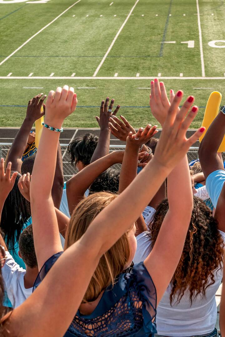 Fans in the stands cheer on the sidelines of the football field.