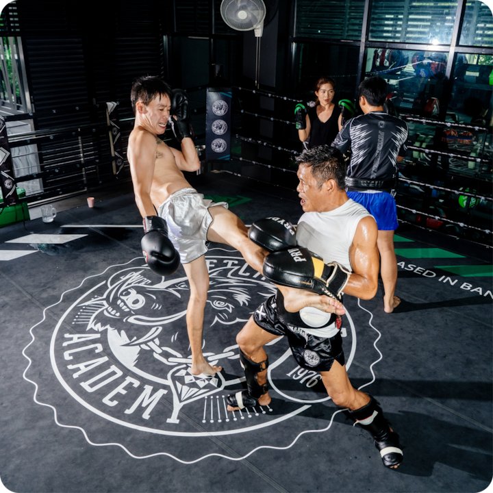 Une séance d'entraînement d'arts martiaux dans une salle de sport, mettant en scène deux personnes qui s'entraînent dans des conditions d'éclairage intense, mettant l'accent sur le mouvement et le contraste.