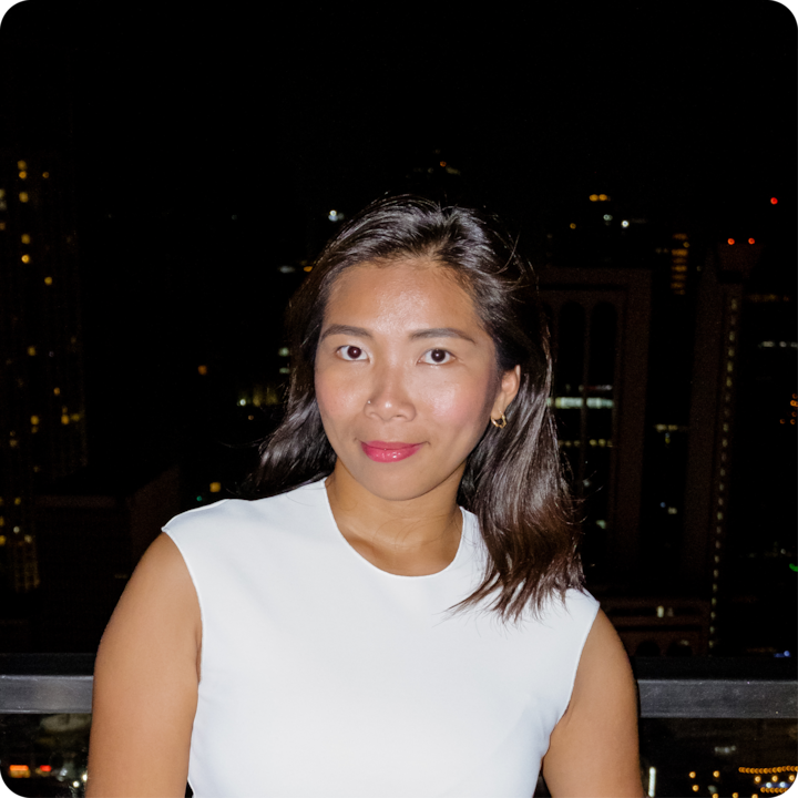 Une personne photographiée de nuit avec des bâtiments urbains très éclairés au loin, illustrant l'utilisation du flash pour améliorer la clarté des portraits dans des environnements à faible luminosité.