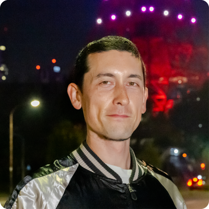 Un portrait pris de nuit à l'aide d'un flash, avec des lumières rouges et violettes vives en arrière-plan, illustrant les techniques de photographie au flash en faible luminosité.