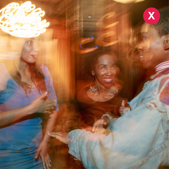 Un groupe de personnes dans un environnement intérieur faiblement éclairé avec du flou de mouvement et des tons chauds, illustrant des situations d'éclairage difficiles.