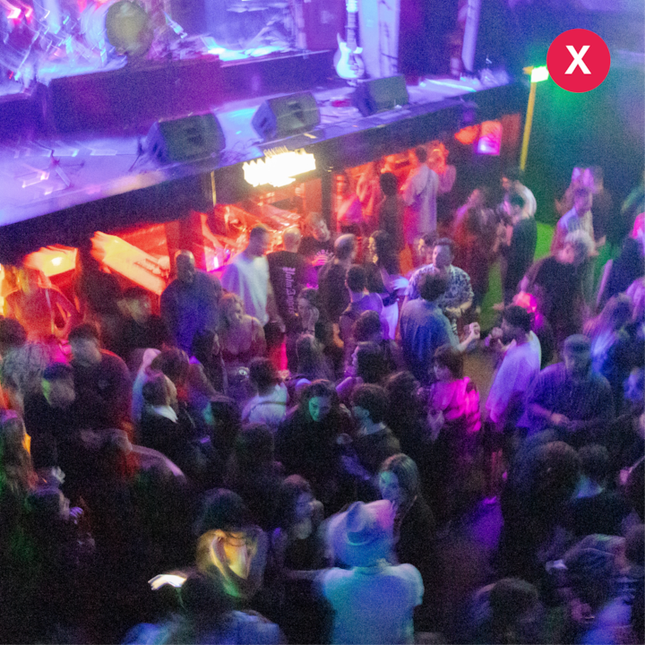Une boîte de nuit bondée avec un éclairage coloré et une scène où est disposé du matériel musical, illustrant des conditions difficiles pour prendre des photos nettes.
