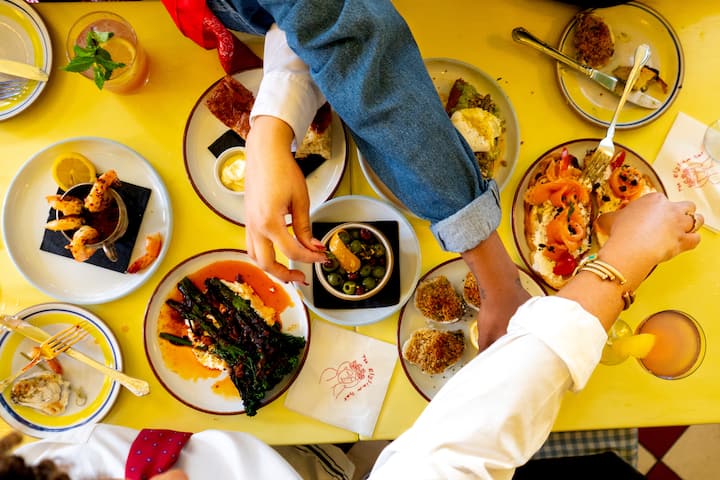 People eating an assortment of dishes around a yellow table