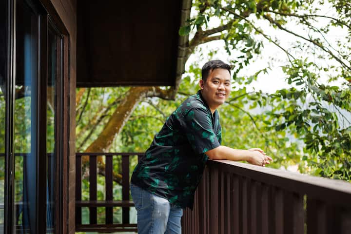 Outdoor view of a wooden balcony with surrounding trees and greenery, highlighting a peaceful and natural setting in Malaysia.