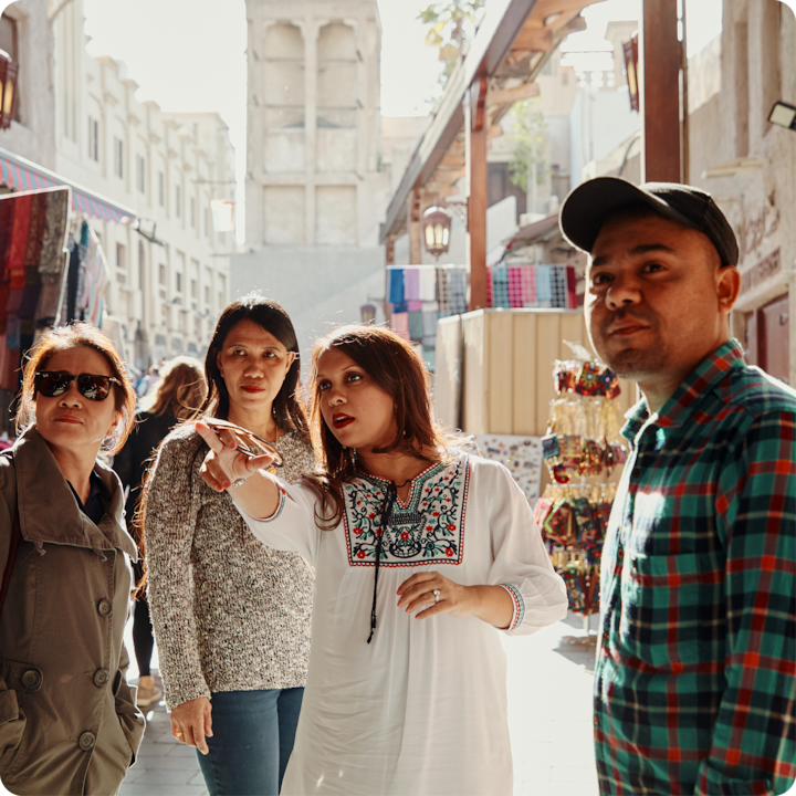 Des participants interagissent et échangent des indications dans un marché culturel, au milieu d'étals présentant des textiles et d'autres produits, illustrant une implication sincère dans une activité.