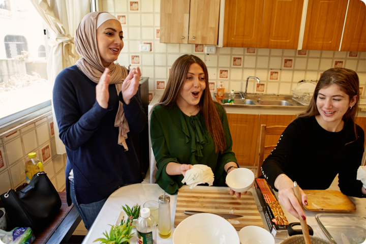 Un groupe de personnes dans une cuisine participe à une activité culinaire interactive. Des bols et des ustensiles sont posés sur la table.