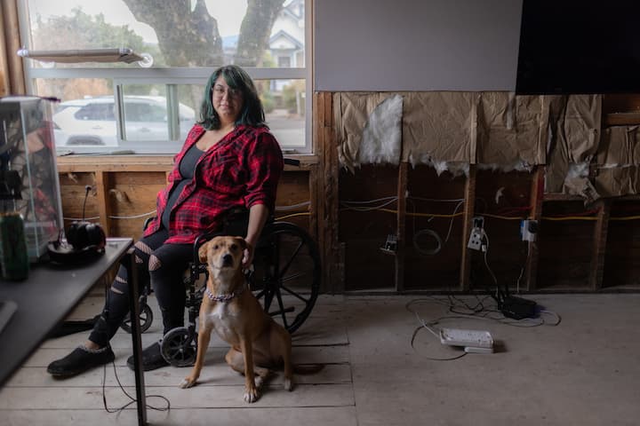 Tawnessa sitter i rullestol med servicehunden sin, Frida.