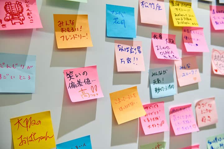 A wall covered with colorful sticky notes written in Japanese, featuring messages about community, friendliness, and positivity.