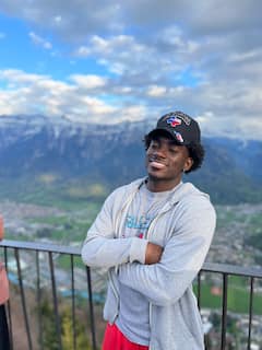 Hasan standing on a balcony in front of a mountain view