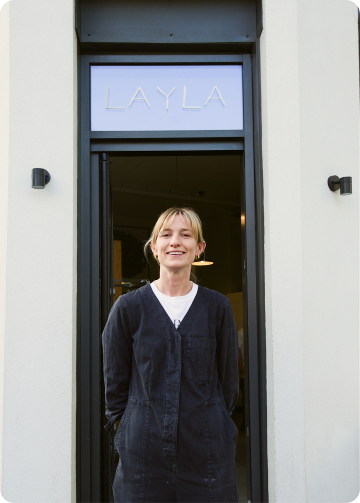 Une personne se tient devant une porte ouverte, révélant un intérieur moderne avec des luminaires suspendus.