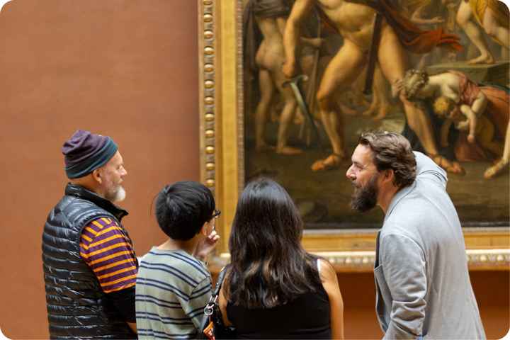 Quatre personnes se tiennent devant un tableau classique encadré dans un musée, discutant et examinant les détails complexes de l'œuvre d'art, qui comprend des figures humaines dramatiques.