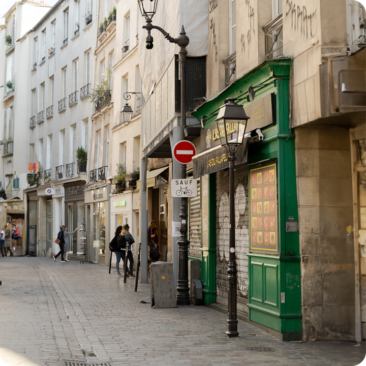 Une rue pittoresque dans une ville, avec des façades de bâtiments rustiques, des lampadaires et des boutiques aux volets fermés, illustrant le charme d'un quartier européen.
