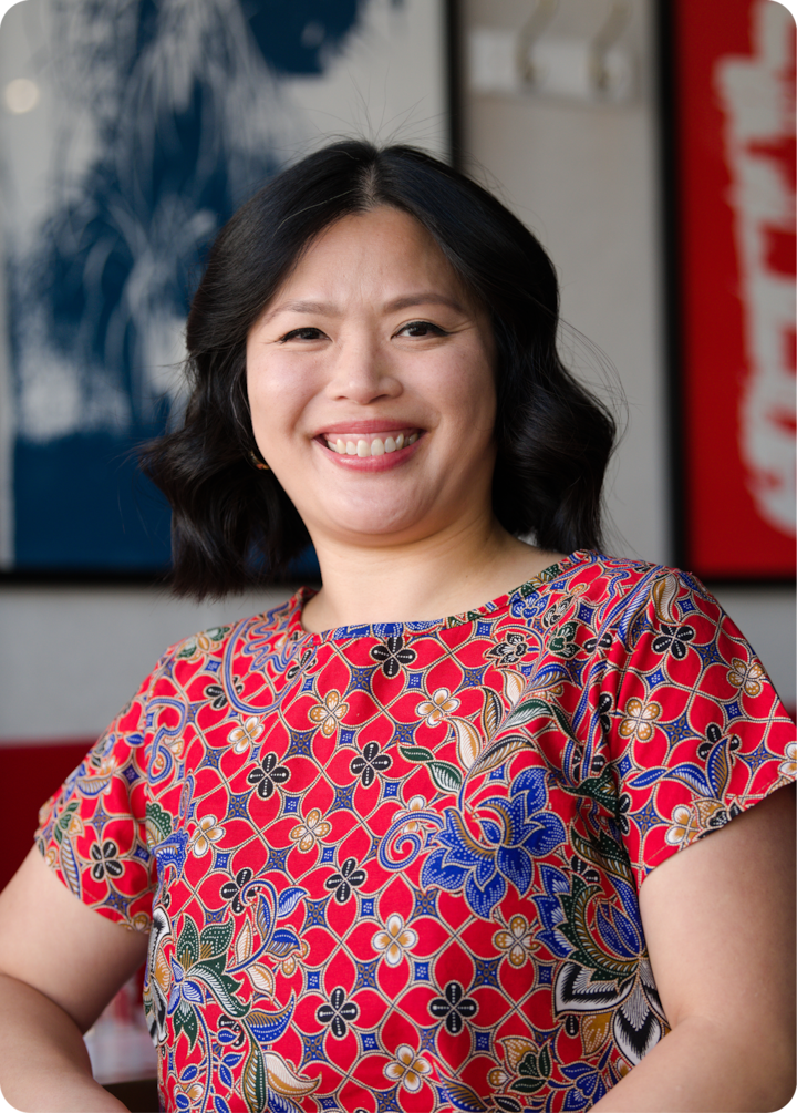 Gros plan sur un haut coloré avec des motifs floraux complexes, sur un fond d'art mural abstrait bleu et rouge.