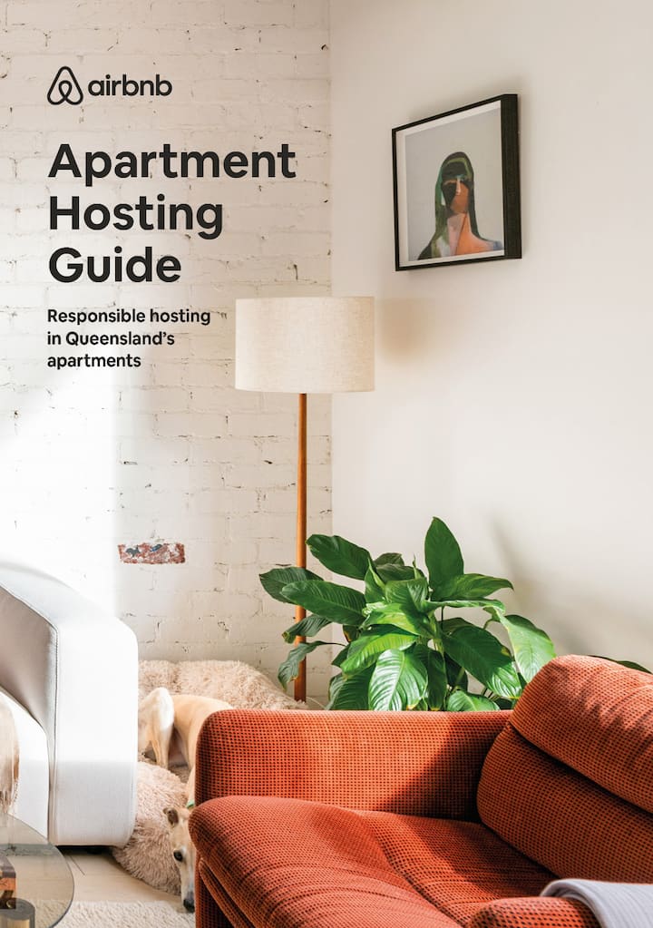 Living room with a red armchair, green indoor plant, white lamp, and framed artwork on the wall. Text overlay reads 'Airbnb Apartment Hosting Guide: Responsible hosting in Queensland’s apartments.'