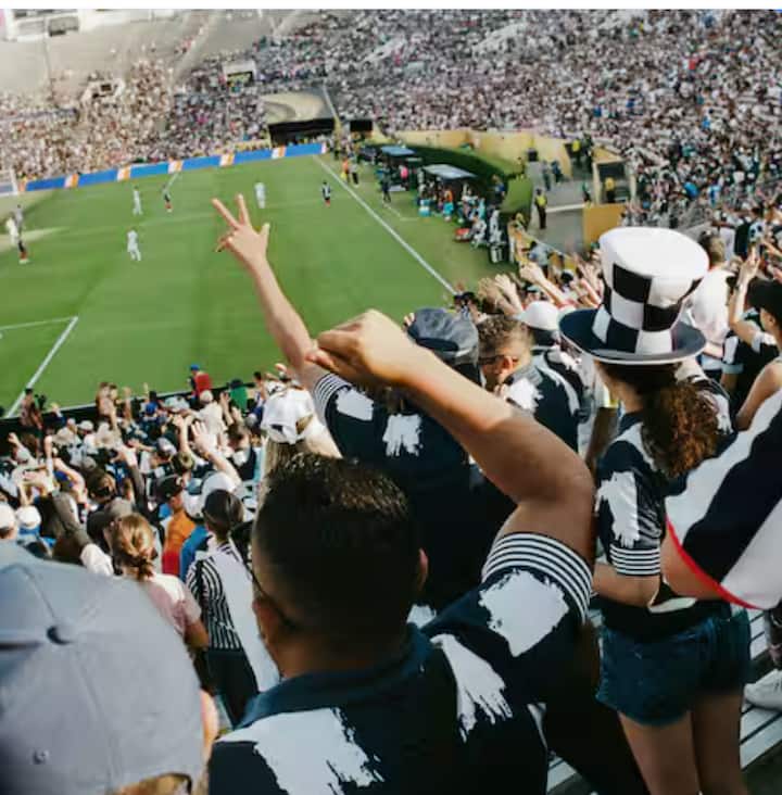 A large crowd of enthusiastic fans watching a soccer match in a stadium.
