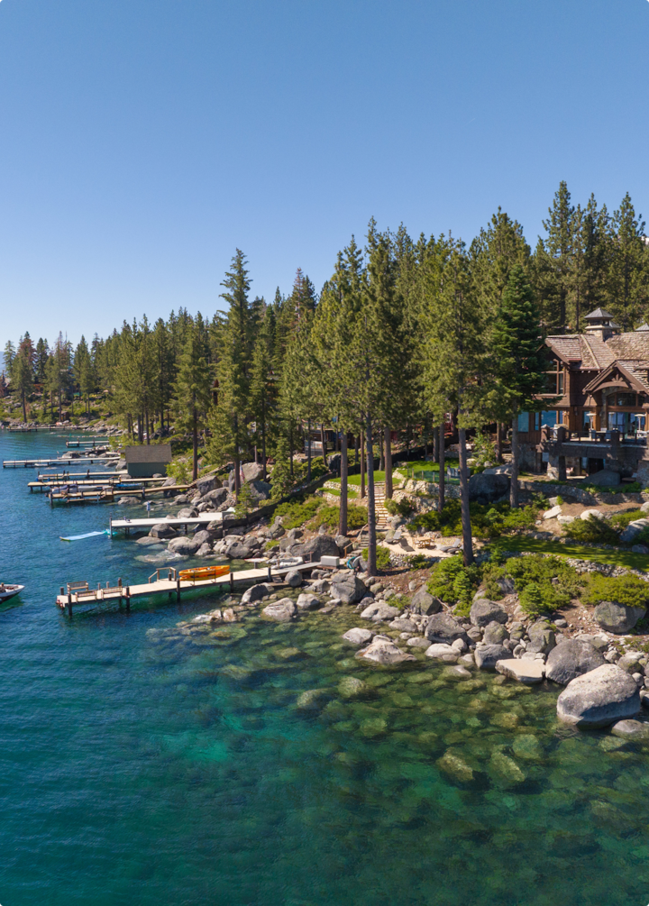 Une propriété de luxe entourée de pins au bord d'un lac aux eaux cristallines, avec des pontons privés.