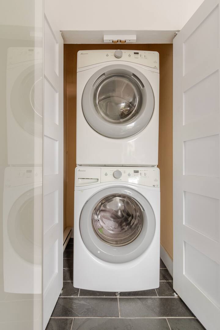 Un lave-linge et un sèche-linge soigneusement disposés dans un espace buanderie encastré, présentant les équipements pratiques disponibles dans le logement.