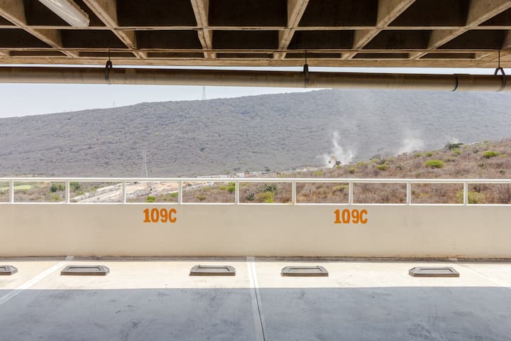Un parking ouvert doté de deux places de stationnement portant la mention 109C, avec une vue imprenable sur des collines escarpées et de la végétation au loin.