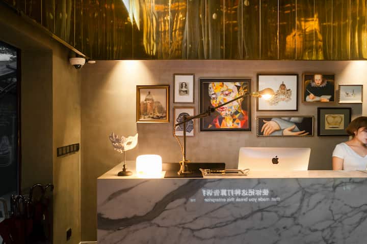 Un bureau de réception en marbre avec un éclairage chaleureux, des éléments décoratifs et une galerie d'art présentant divers tableaux encadrés, créant une ambiance accueillante et élégante.