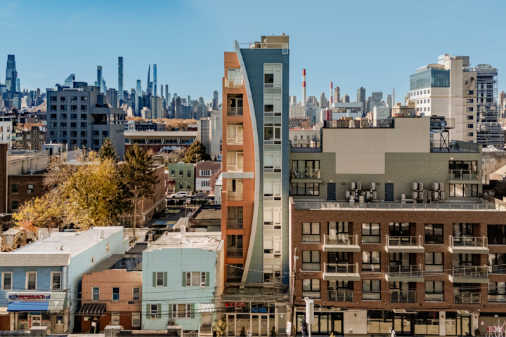 Photo prise du dessus d'un bâtiment unique de plusieurs étages aux accents orange. Il est niché dans un quartier urbain, soulignant ce paysage métropolitain et le ciel dégagé.