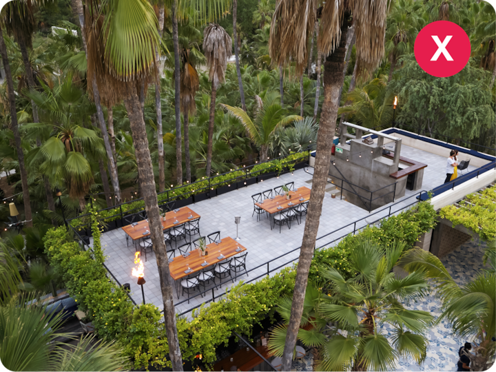Un patio sur le toit offrant une vue panoramique. Il est agrémenté de tables à manger, d'un barbecue et d'une végétation luxuriante. De grands palmiers se trouvent tout autour.