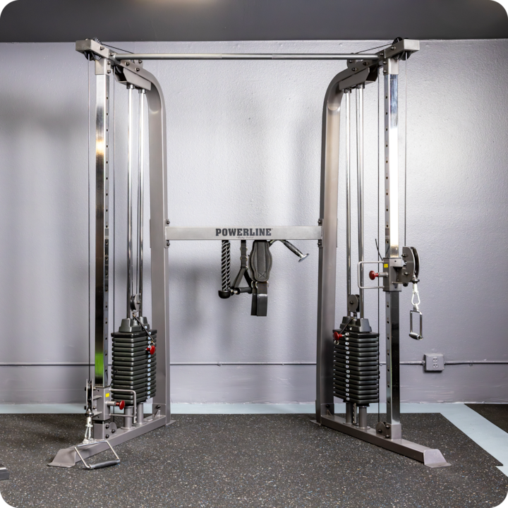 Photo d'une machine de musculation placée contre un mur gris, mettant en avant les équipements mis à la disposition des voyageurs.