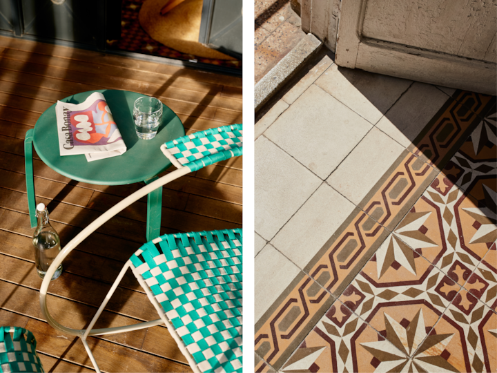 Une terrasse accueillante et baignée par la lumière du soleil sur laquelle sont installés une chaise verte tissée et une table d'appoint, où sont posés un journal et un verre d'eau.
